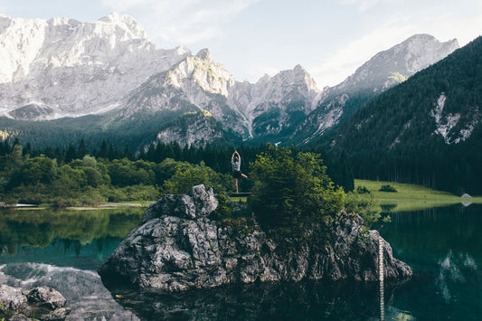 person standing on rock formation surrounded by body of water