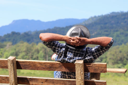 a man resting his head on a wooden fence
